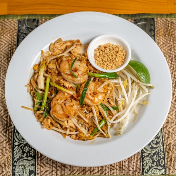 Pad Thai with shrimp, chicken, bean sprouts, green onions, lime, and crushed peanuts.