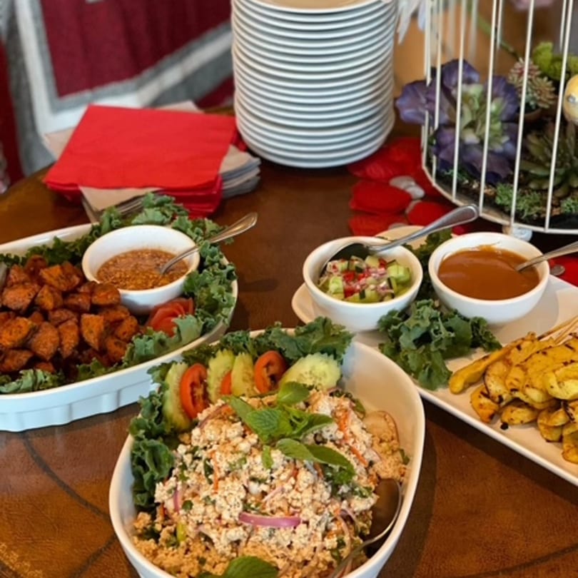A buffet spread with various Thai dishes, including larb, satay, and sweet potatoes.